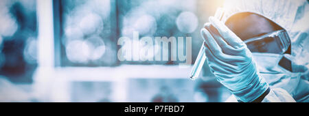 Protected scientist looking at a dangerous liquid in test tubes Stock Photo