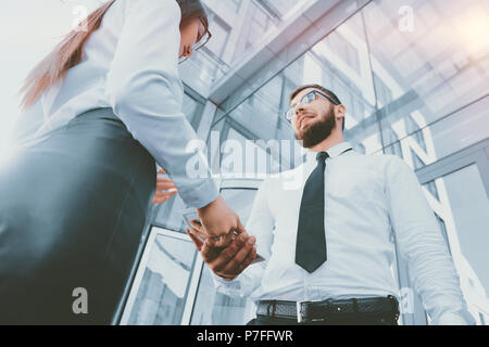 A girl gives a man in the hands of money in the background of an office building. Payment for services. Salary in the envelope. Bribe. corruption. Sha Stock Photo