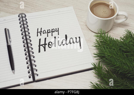 Happy Holiday written on notebook placed on top of wood desk. Festival and celebration concept. Stock Photo