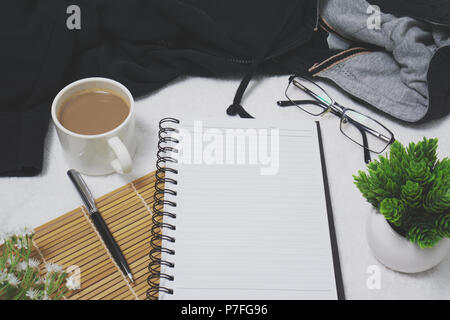 Blank spiral notebook page on cozy white tablecloth. Rustic home office desk. Stock Photo