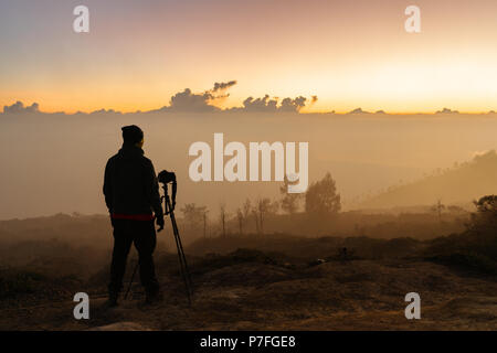 Photographer with camera and tripod waiting sunrise on the mountain peak Stock Photo