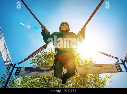 Little boy jumping on bungee trampoline. The boy in the time of the jump with a smile, joy and happiness on her face. A bright Sunny sky. Stock Photo