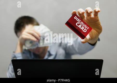 Online shopping and payment. Handsome man showing a credit card and using laptop browsing internet. Young businessman holding a discount card and the  Stock Photo