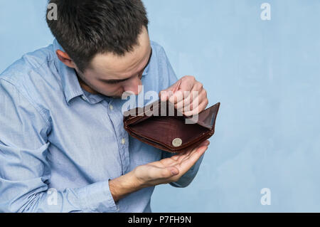 The guy pulls out the last ruble out of an empty purse. Poverty and unemployment. Man with no money. Businessman holding empty wallet. Stock Photo