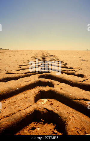 Tractor tyre tracks in sand disappearing into the horizon Stock Photo
