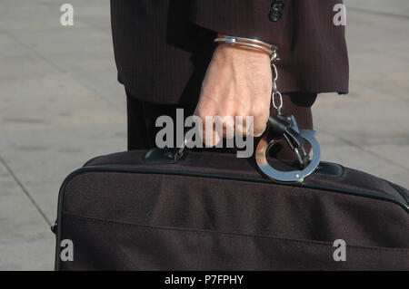Businessman with handcuffs on bag and wrist, Germany Stock Photo