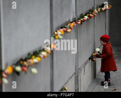 (180706) -- BERLIN, July 6, 2018 (Xinhua) -- A girl puts flowers onto a part of the former Berlin Wall during a memorial activity to commemorate the 25th anniversary of the fall of the Berlin Wall in Berlin, Germany, on Nov. 9, 2014. (Xinhua/Zhang Fan) (wtc) Stock Photo