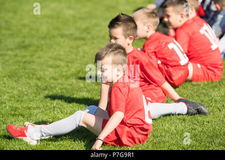 Kids soccer football - young children players sitting in out at match on soccer field Stock Photo