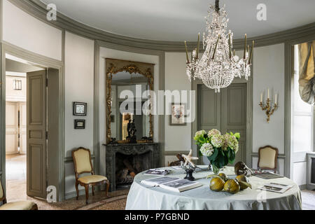 Glass chandelier above table with gilt framed mirror in circular room of 18th century chateaux, St Remy de Provence Stock Photo