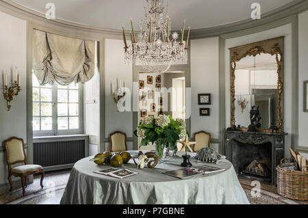 Glass chandelier above table with gilt framed mirror in circular room of 18th century chateaux, St Remy de Provence Stock Photo