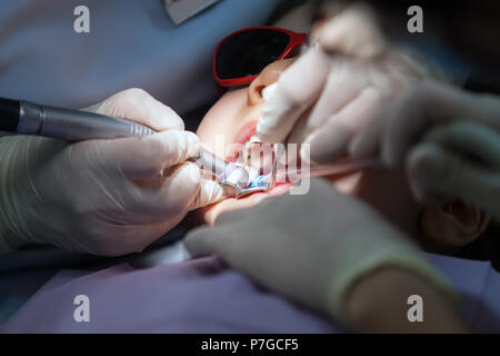 Little Girl on Dentist Chair, Kid is taking Dental Procedure Stock Photo