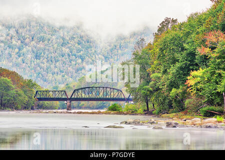 New River Gorge wide canyon, water, bridge during autumn golden orange foliage in fall by Grandview in morning fog, hills Stock Photo