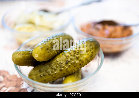 Macro closeup of traditional Russian or Ukrainian juicy kosher Jewish green pickles in bowl as appetizer, side dish on table Stock Photo