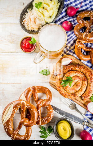 Oktoberfest food menu, bavarian sausages with pretzels, mashed potato, sauerkraut, beer bottle and mug, white wooden background copy space top view Stock Photo