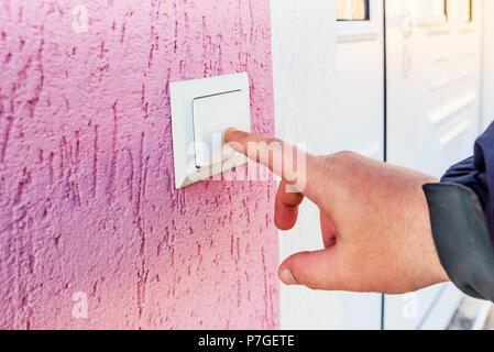 hand ringing on doorbell on pvc front door Stock Photo