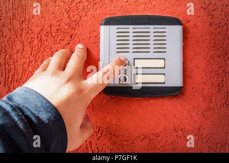 hand ringing on doorbell on pvc front door Stock Photo