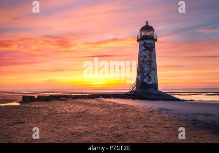 Sunset at Point of Ayr Lighthouse on Talacre Beach, Wales, with colourful sky in the background and low tide Stock Photo