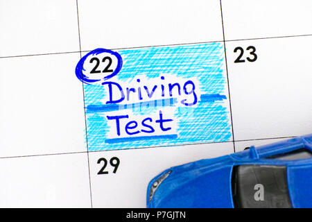 Reminder Driving Test in calendar with blue toy car. Close-up. Stock Photo