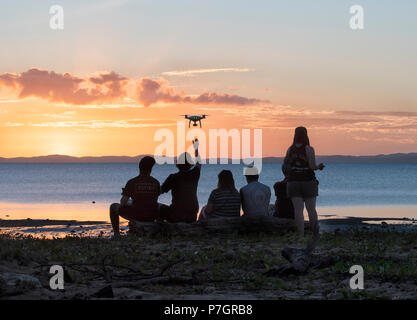 Silhouettes of a group of persons flying a drone at sunset, Loyalty Beach, Seisia, Cape York Peninsula, Far North Queensland, FNQ, QLD, Australia Stock Photo