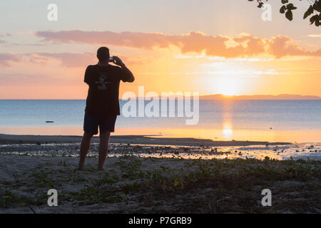 Silhouette of an adult male taking a picture of the sunset, Loyalty Beach, Seisia, Cape York Peninsula, Far North Queensland, FNQ, QLD, Australia Stock Photo