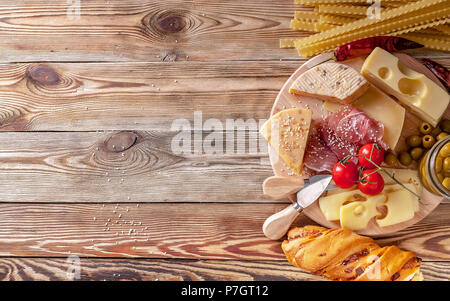 Cheeses, jamon, baguette, pasta mafaldine and olives on a wooden background. Close-up Stock Photo