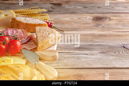 Cheeses, jamon, baguette, pasta mafaldine and olives on a wooden background. Close-up Stock Photo