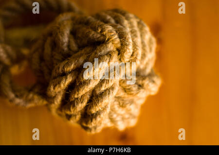 fender - marine knot of thick brown rope on a wooden background, closeup Stock Photo