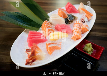 Mixed sliced fish sashimi on ice in white bowl. Sashimi Salmon Tuna Hamachi Prawn and Surf Calm set, raw fish, japanese food in Asian restuarant. Stock Photo