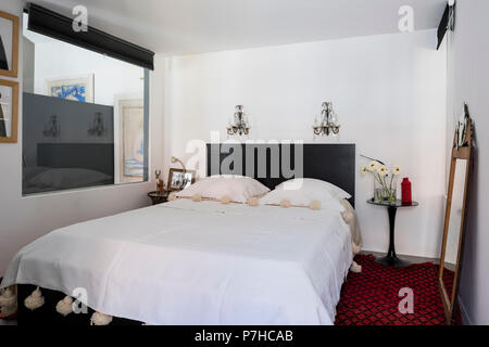 Elegant sleeping area in modern open plan apartment with red morccan reg and antique glass wall sconces Stock Photo