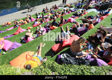 People relaxing on the steps at Granary Square, Kings Cross, to watch the Everyman Summer of Love Film Festival, in north London, UK Stock Photo