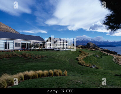 Modern single storey house beside the ocean in New Zealand with mountains in the background Stock Photo