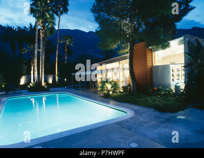 Underlit swimming pool in front of modern Californian house lit from within at night Stock Photo