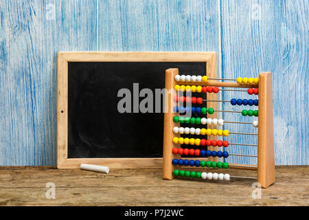 Blank vintage chalkboard and toy abacus on rustic table with blue wood background Stock Photo