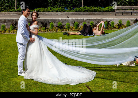 A Visiting Bride and Groom From Hong Kong Pose For Wedding Photography On The Lawns Outside St Paul’s Cathedral, London, England Stock Photo