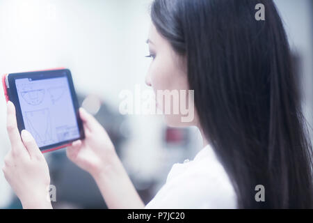 Female engineer looking at technical drawings on a digital tablet Stock Photo