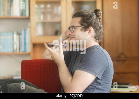 Man sitting in living room talking on mobile phone Stock Photo