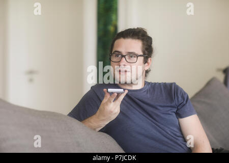Man sitting in living room talking on mobile phone Stock Photo