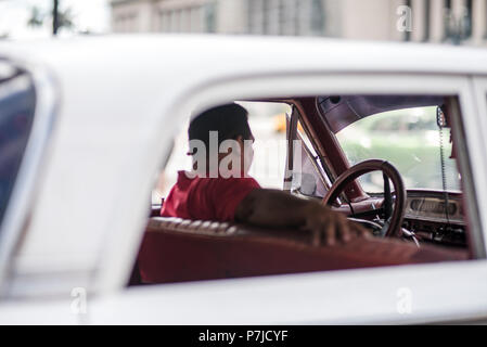 A cab driver waits for a tourist to climb into his classic car for a ride in Havana, Cuba. Stock Photo