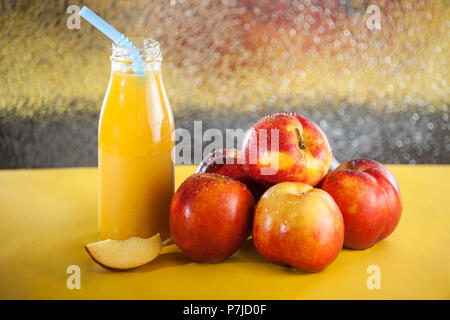 Bottle of orange juice next to a stack of apples Stock Photo