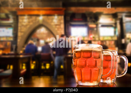 Two glass mugs of cold bar in a typical Irish pub setting Stock Photo
