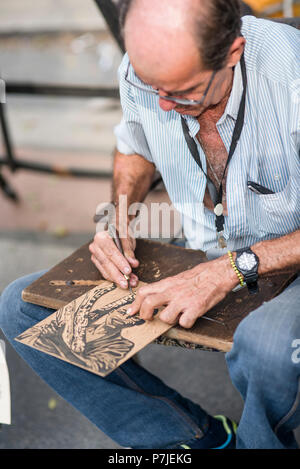 A Cuban artist works on his prints at an outdoor market in Havana. Stock Photo