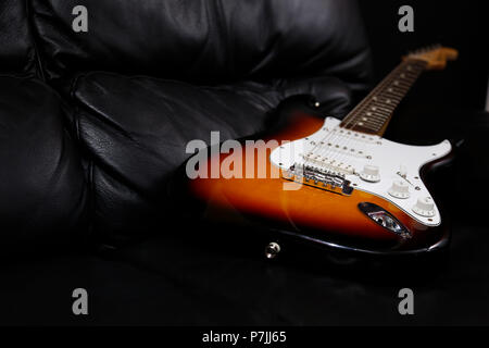 Electric guitar lying on sofa Stock Photo