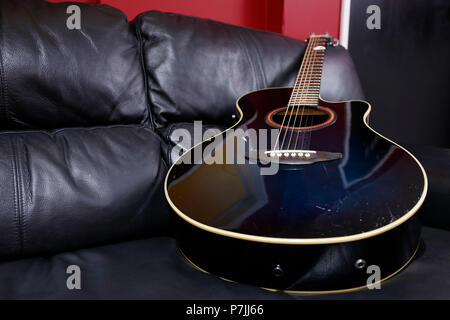 Acoustic guitar laying on sofa Stock Photo