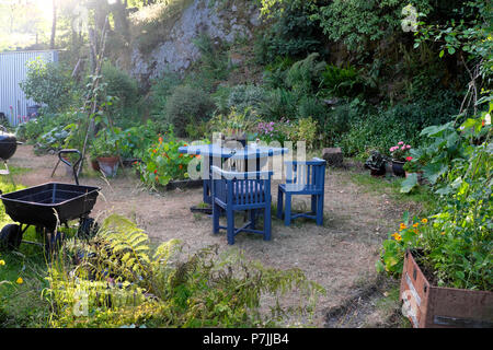 Blue vintage garden furniture table chairs with wagon and parched lawn in a small backyard country garden in hot June summer Wales UK  KATHY DEWITT Stock Photo