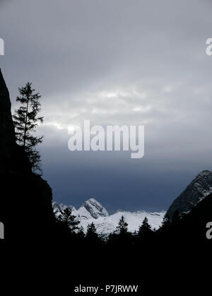 Dark cloud layer above snow-covered mountains, silhouette of a forest, Upper Bavaria Stock Photo