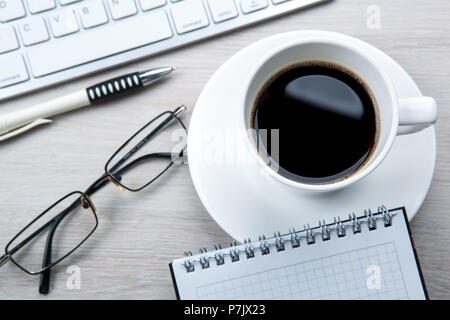white cup of black coffee, glasses, keyboard on the desktop Stock Photo