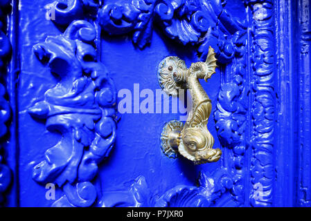 Vintage style dolphin shaped brass door knocker on vivid blue carved wood door, Cuzco, Peru Stock Photo