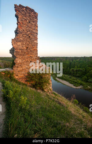 old ruined wall on hill near large river surrounded by summer forest Stock Photo