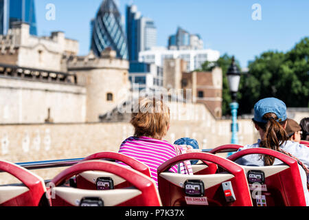 London, UK - June 22, 2018: Back of women tourists looking at city cityscape view, tower fortifications wall buildings on street road double decker re