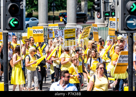 London, United Kingdom - June 22, 2018: People holding up signs at Cystic Fibrosis protest in UK England to make Orkambi medicine drug free, yellow co Stock Photo